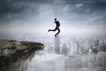 eine Frau im Anzug springt von einer Klippe über einer Grossstadt.